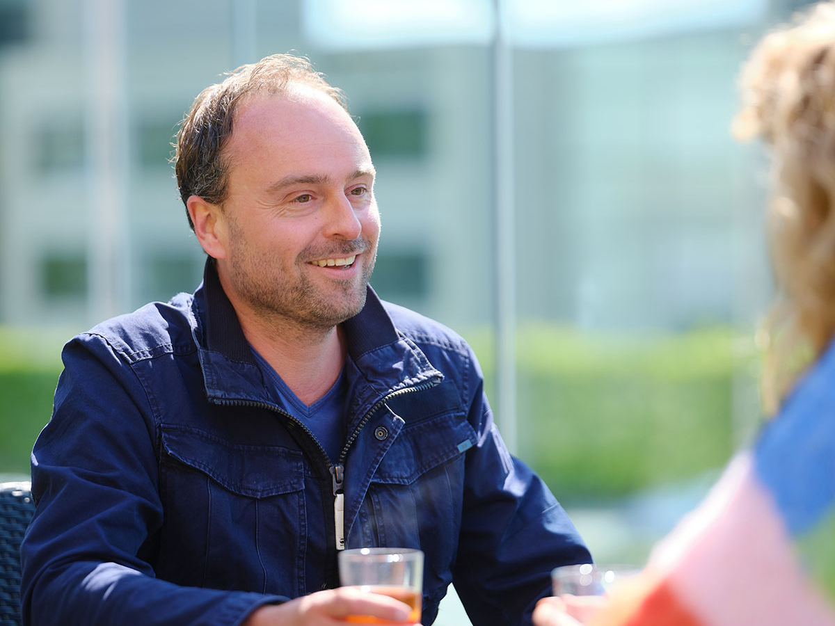 Foto van deelnemers op het balkon van het onderzoekscentrum met een glas drinken